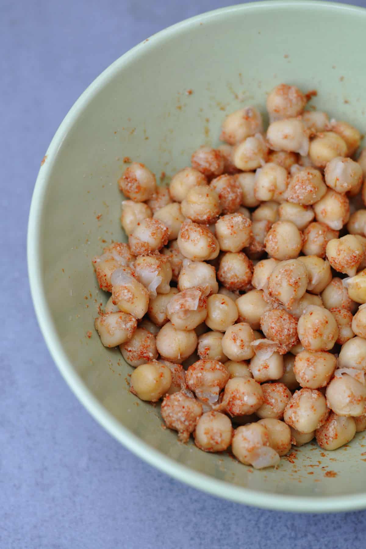 Cooked chickpeas with spices mix of nutritional yeast, chili powder and salt in a bowl