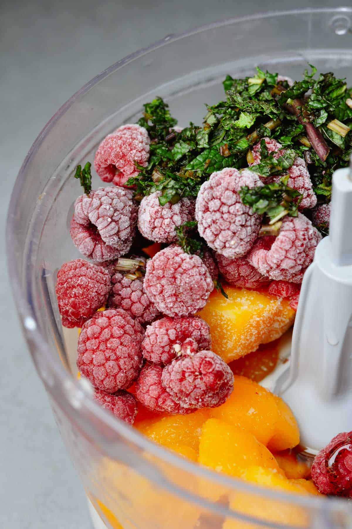 Frozen raspberries, peaches and mint with vegan soy yogurt in a food processor