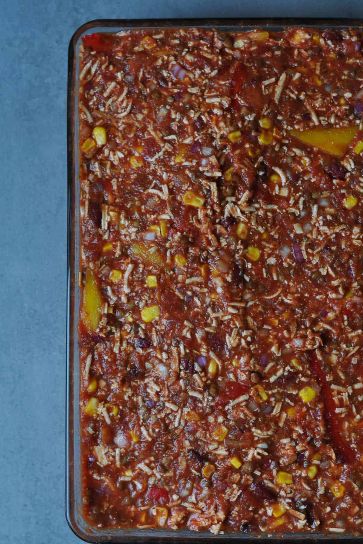 Mix of ingredients for vegan chili con carne (sin carne) in a glass baking tray