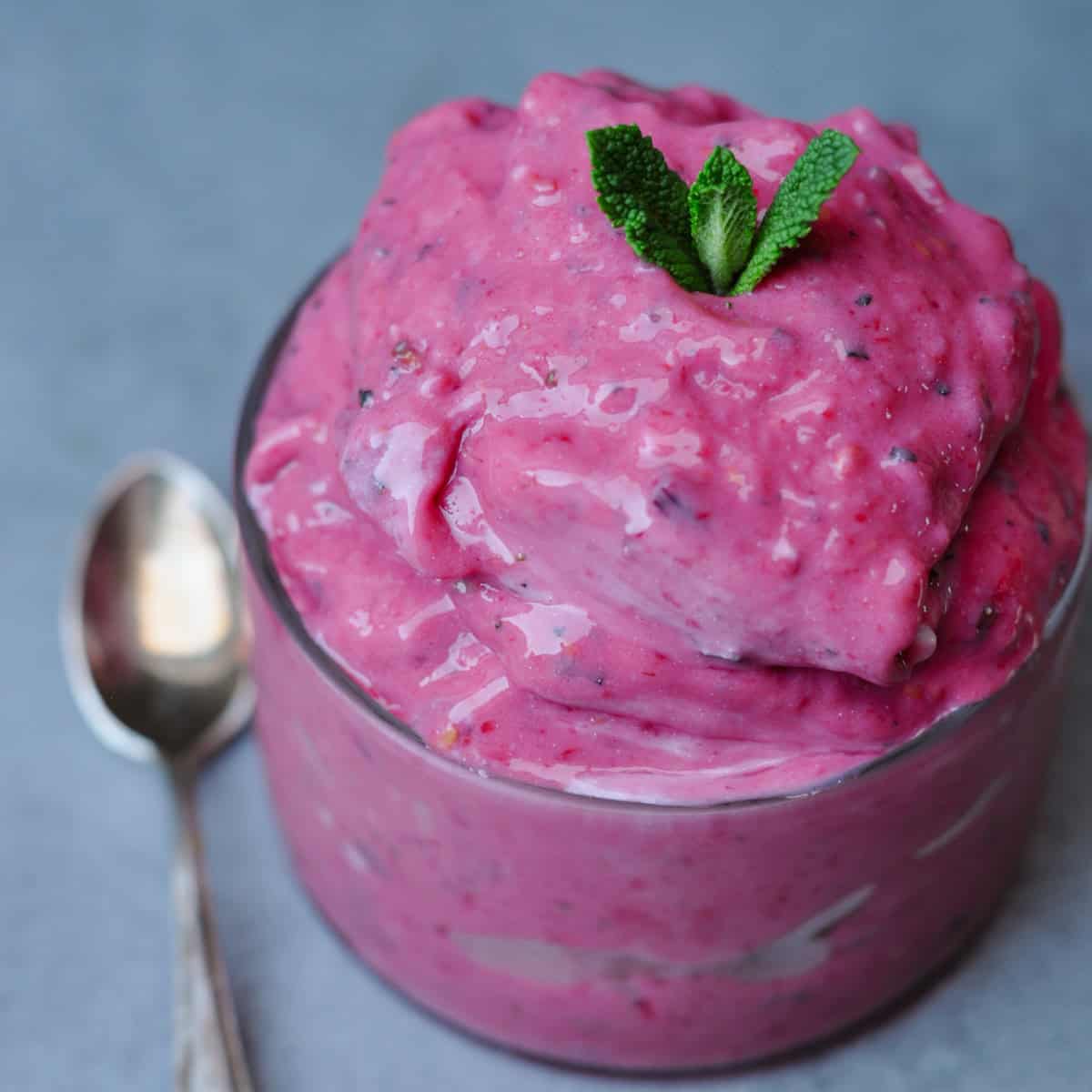 Vegan frozen yogurt with raspberries, peaches and mint in a glass