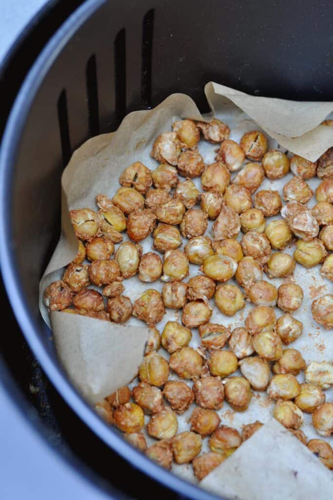 Crunchy roasted chickpeas (oil-free)  with spices mix of nutritional yeast, chili powder, and salt in an air fryer basket