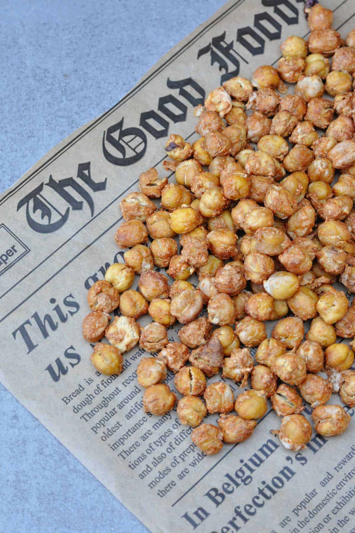 Crunchy roasted chickpeas (oil-free) with spices mix of nutritional yeast, chili powder, and salt on a piece of newspaper