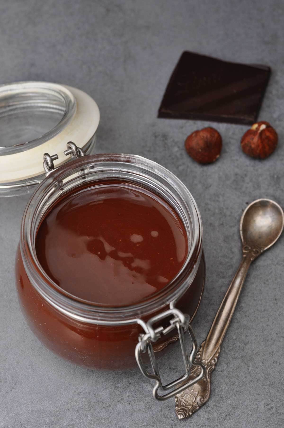 vegan gianduja chocolate spread with dark chocolate in a small glass container on a table.