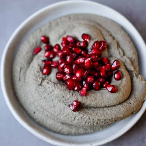 black sesame paste hummus with pomegranate seeds topping on a plate