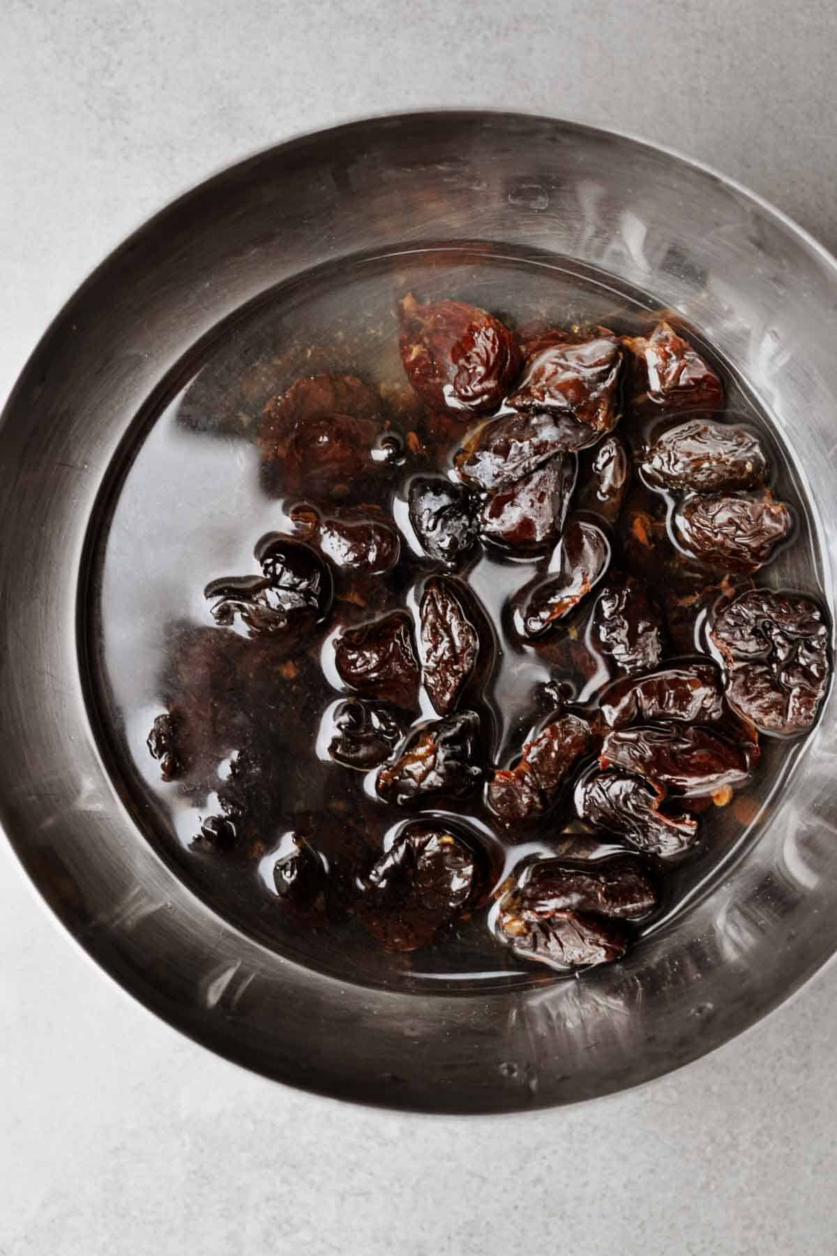 dried plums in hot water in a bowl.