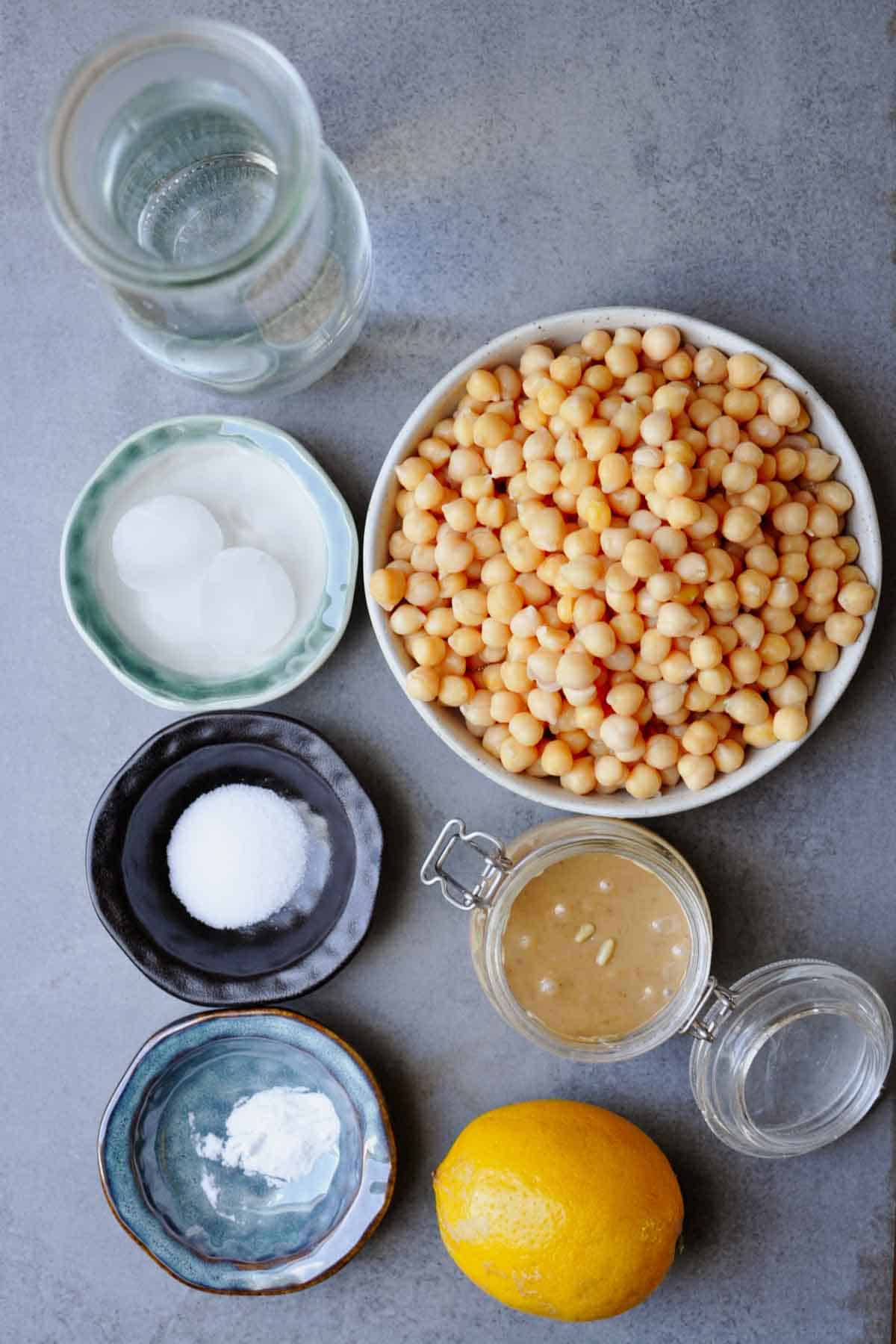 ingredients for making simple roasted pine nut butter hummus recipe (without tahini) on a gray table.